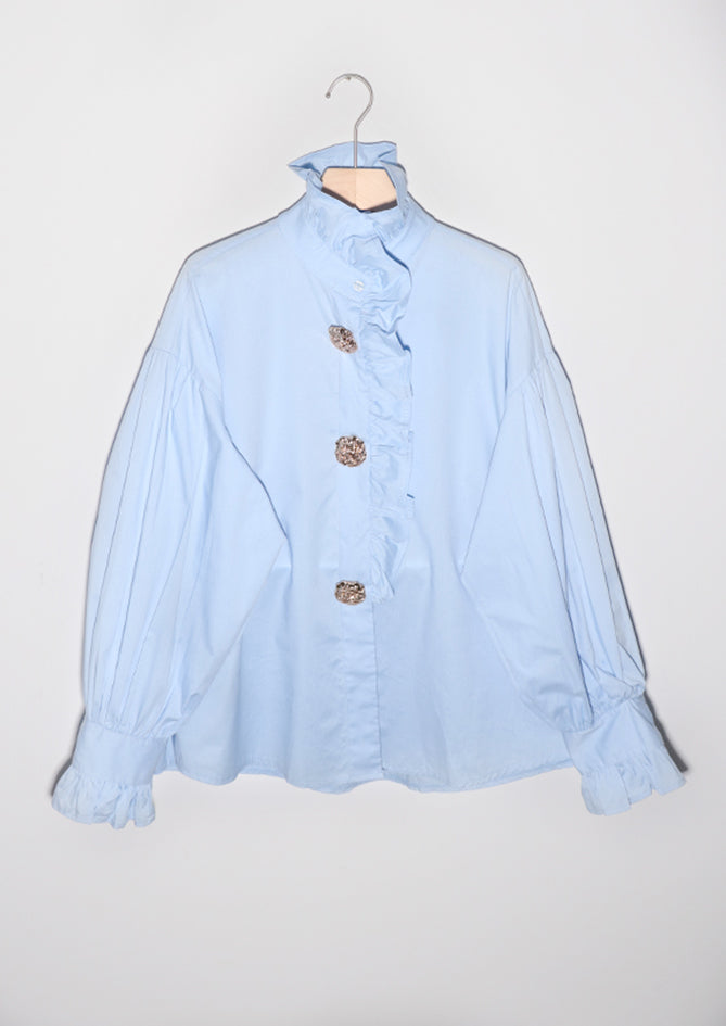 Light blue blouse with buttons on a hanger against a white background