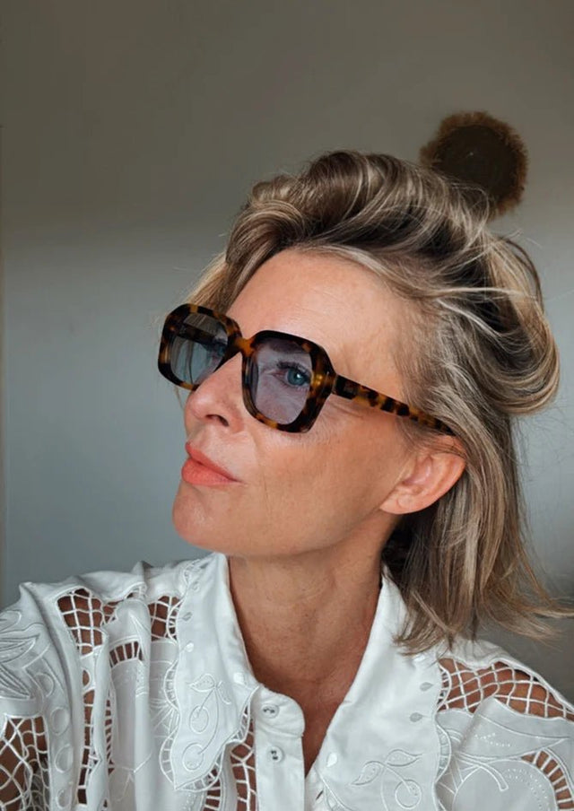 Lifestyle portrait featuring Phlox sunglasses – elegant women’s eyewear by AndBloom with bold blue lenses and classic style