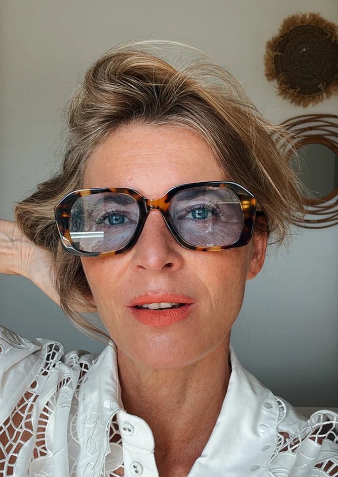 Woman wearing Phlox sunglasses by AndBloom – matte tortoise frame with vibrant blue lenses, UV400 & blue light protection
