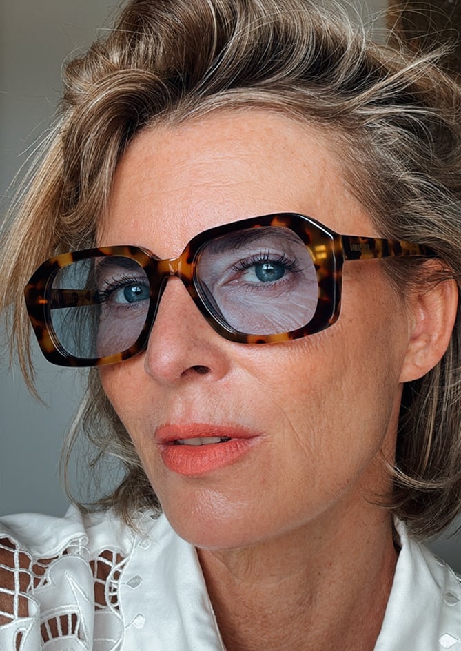 Model showcasing Phlox sunglasses – AndBloom fashion eyewear with tortoise frame, vibrant blue lenses and timeless elegance